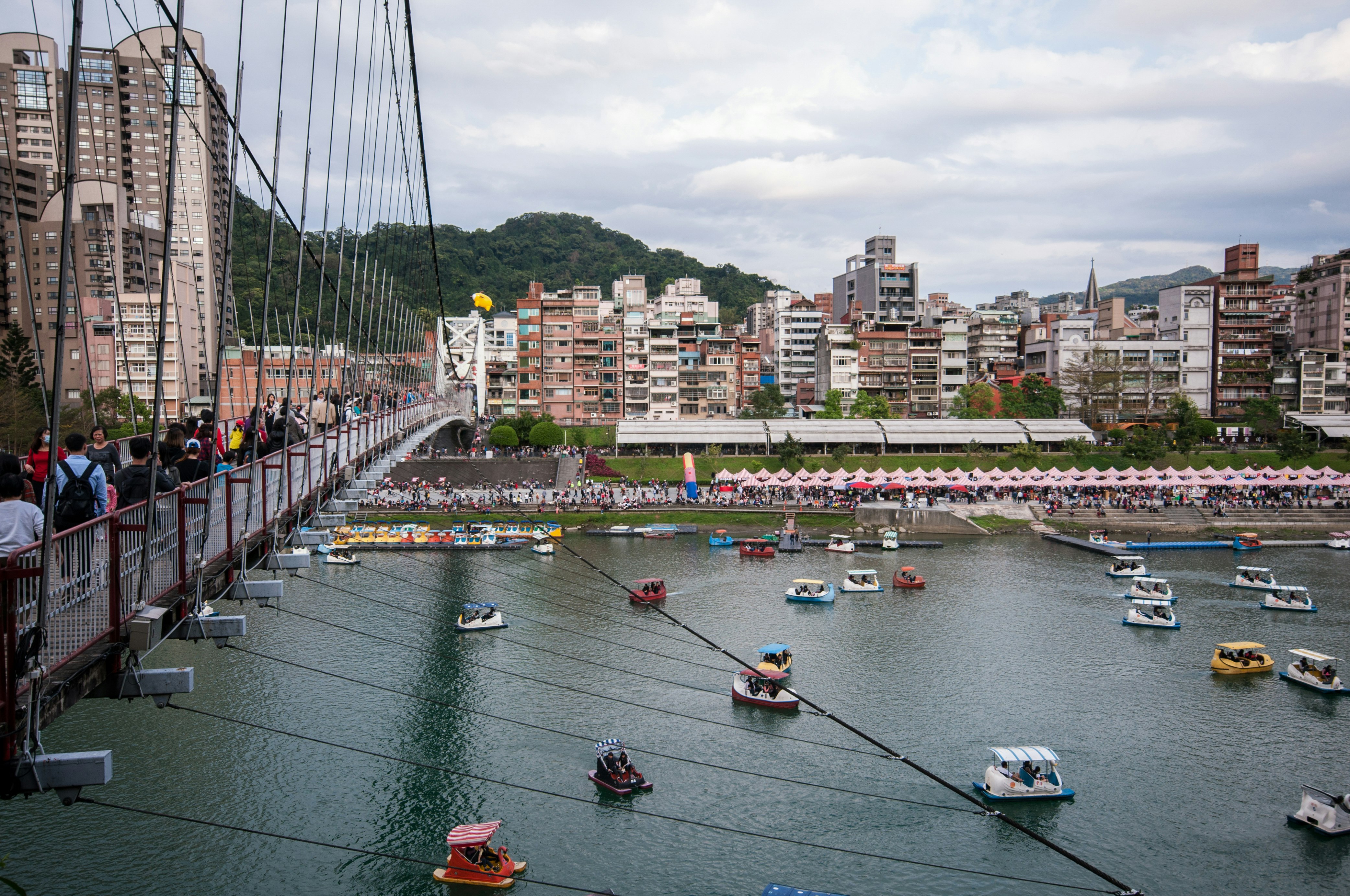 people riding on boat on river near city buildings during daytime